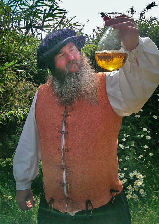 A picture of a marvellous history visitor dressed as an alchemist holding a bottle containing some amber coloured liquid up to look at